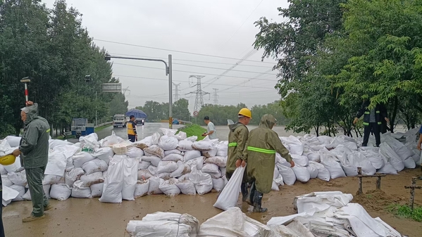 项目抢险人员在沈阳西站西南侧的东甸子村桥南头公路段与大堤接口装堵沙袋.jpg